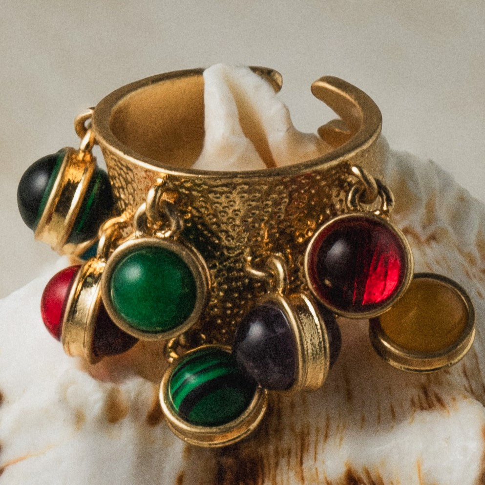 Gold bracelet with colorful gemstones on a shell background