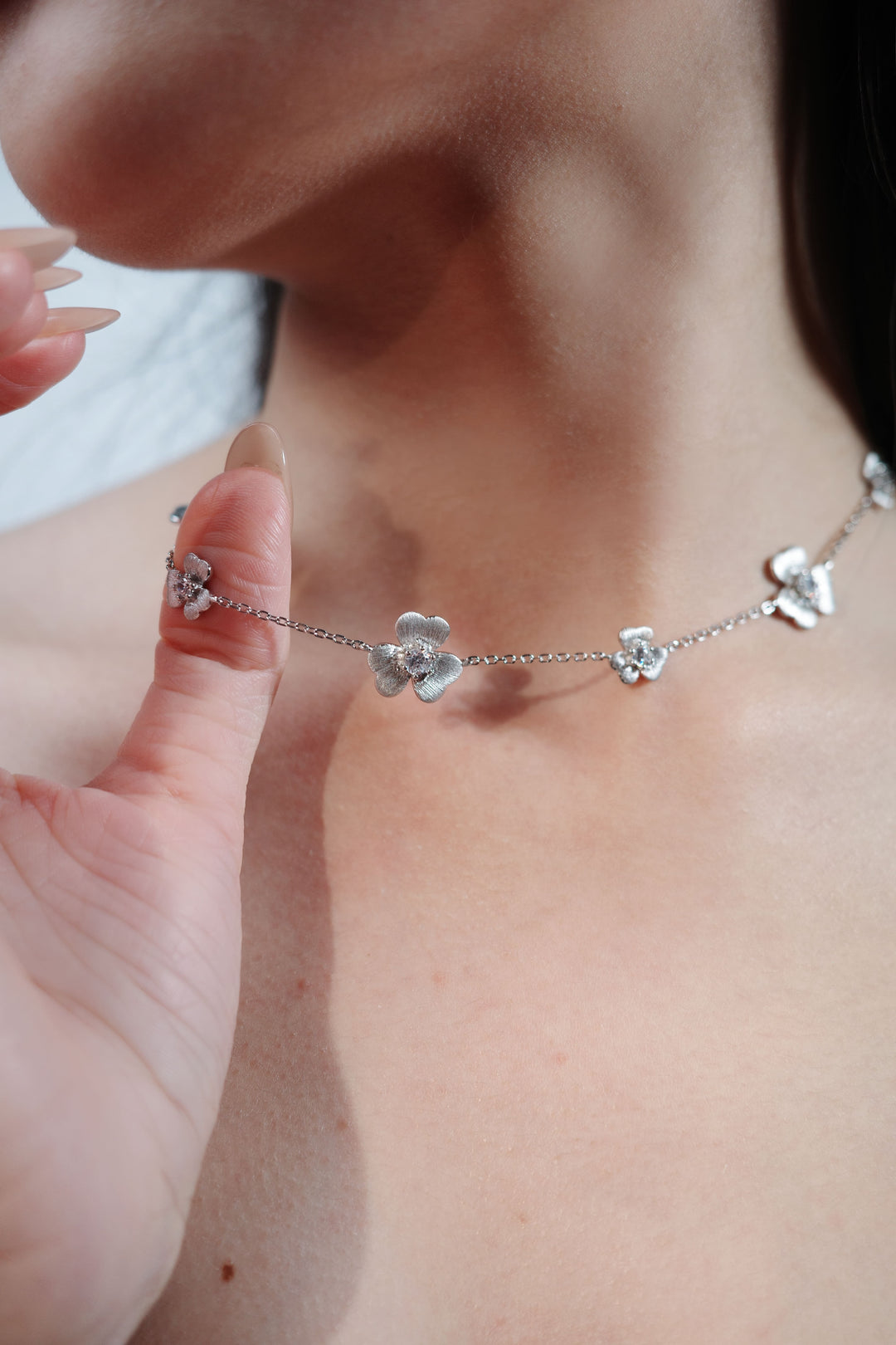 Sterling silver floral necklace with textured flower charms on a woman's neck