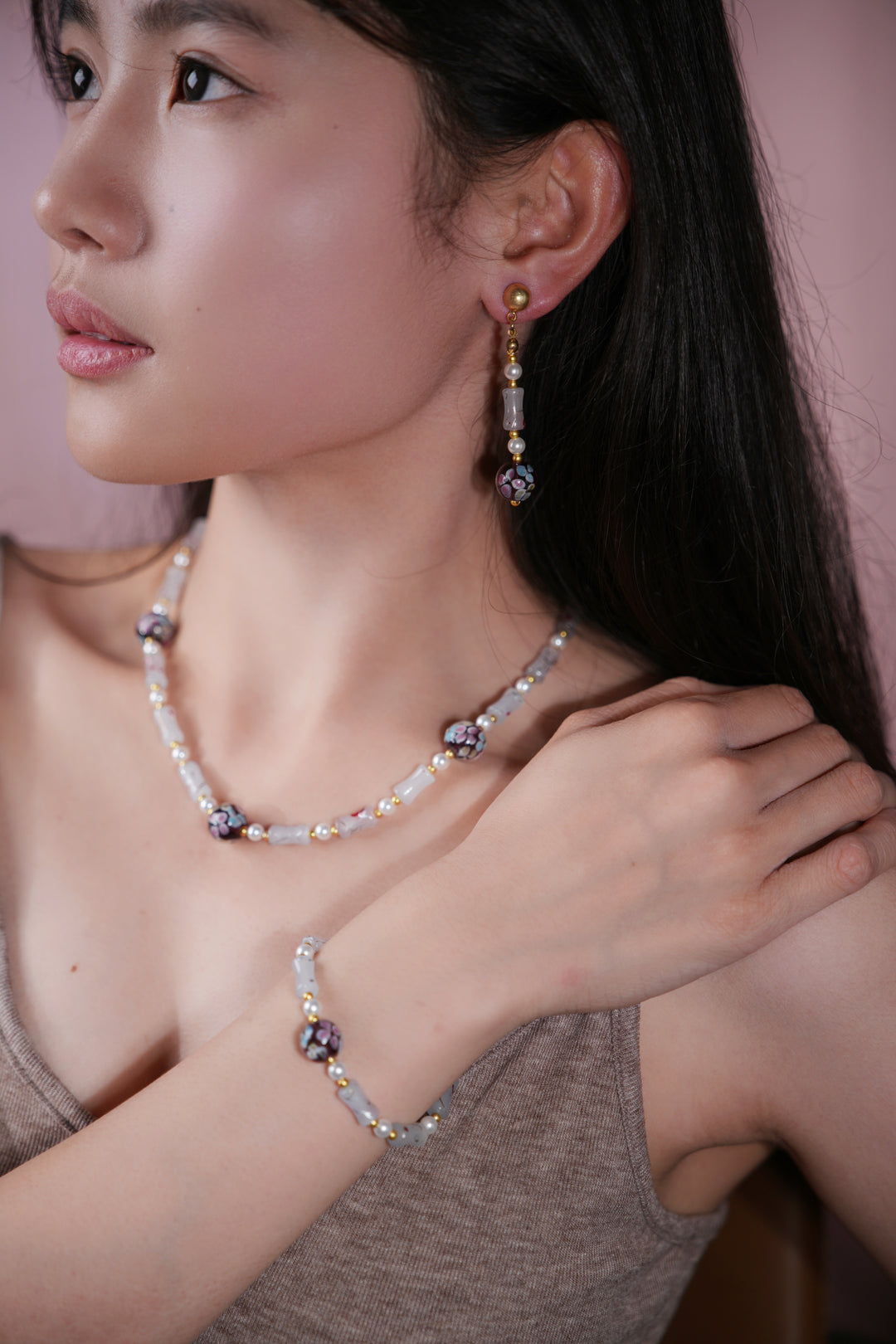 Woman wearing purple floral liu li drop earring, matching necklace and bracelet