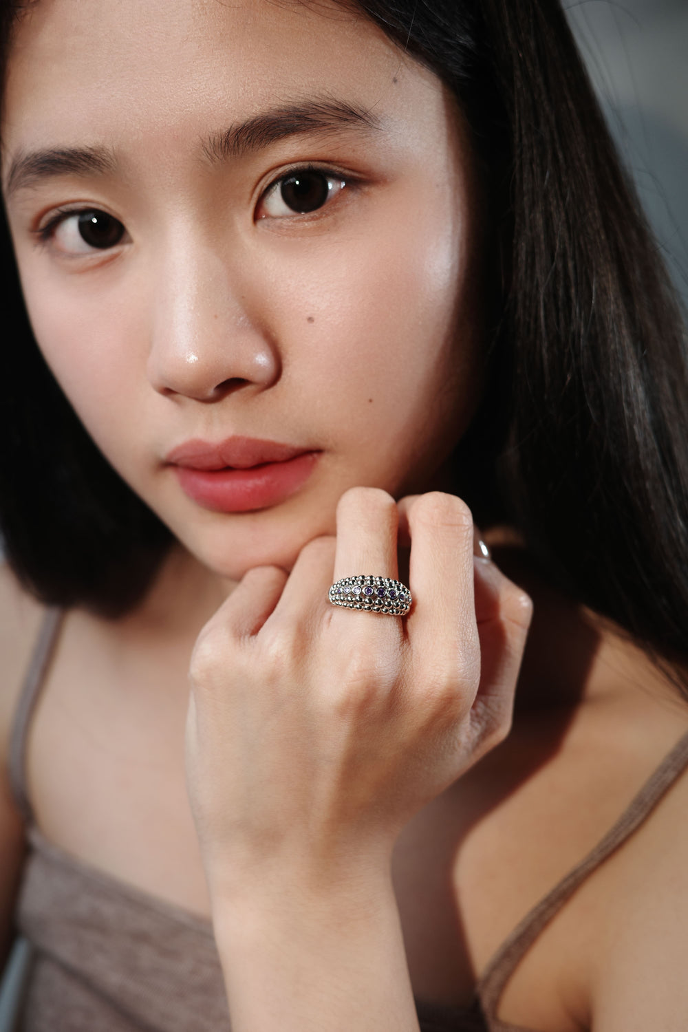 Woman wearing a silver ring with violet stones on her finger, close-up jewelry shot