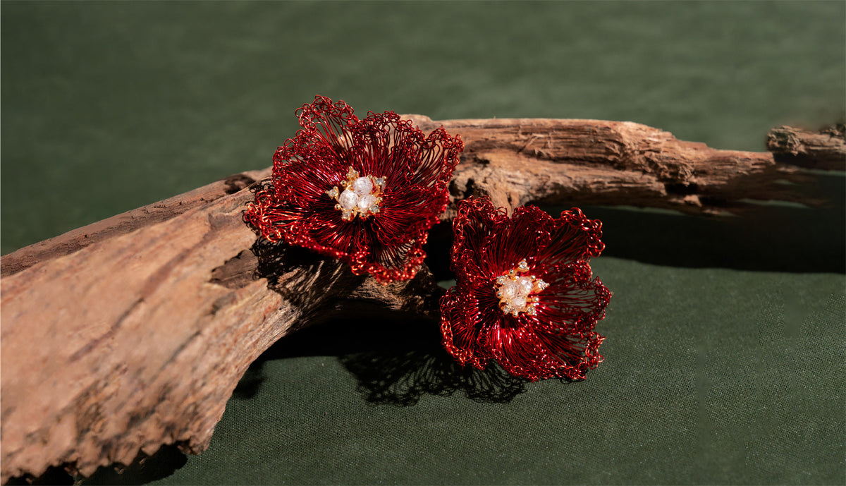 Red wire flower earrings with pearl centers on driftwood, green fabric background - be fruitful jewelry
